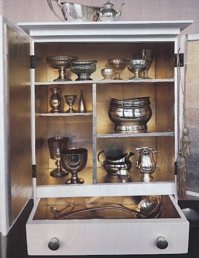 The cabinet is a junk-store find that was sanded and painted, then lined with squares of silver tea paper. The sterling-silver and mercury-glass objects displayed in and on it stand out nicely from the burnished background. The cabinet is a junk-store find that was sanded and painted, then lined with squares of silver tea paper. The sterling-silver and mercury-glass objects displayed in and on it stand out nicely from the burnished background.