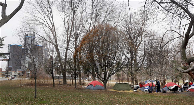 In a photo from Wednesday, 17 December 2014, Charles Floyd Jones picks up trash at the tent city on the eastern edge of downtown Detroit. Jones can only hope that the city&rsquo;s good fortune trickles down to him and the 10 other residents of a tent city that&rsquo;s sprouted in the shadow of a resurgent downtown where rental occupancy is close to full and retail square-footage fetches top dollar. Jones and others in this makeshift community of seven tents say they have nowhere else to go. Photo: Carlos Osorio / AP Photo