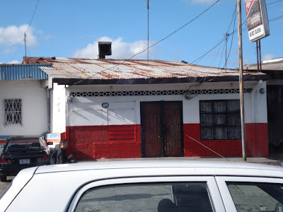 The practical buildings in Costa Rica are a lot like this -- cement walls with tin roofs.  Sturdy against earthquakes and hurricanes, and they keep out the rain.  They also don't get moldy in the parts of the country that are humid.