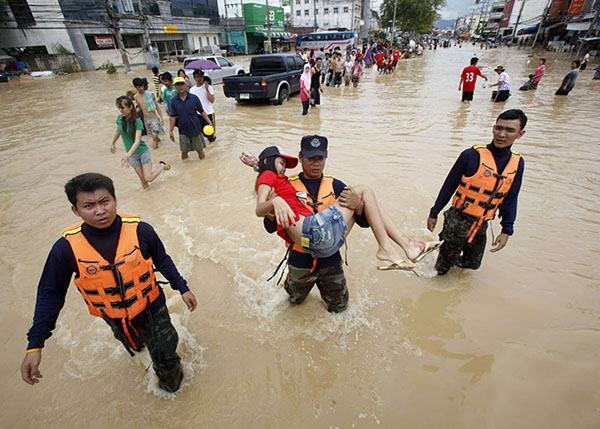 Rescuers in Thailand carry a woman through floodwaters to safety. thaitravelnews.net