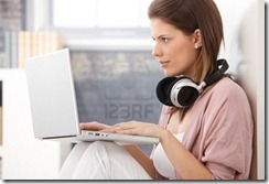 9435067-young-woman-busy-using-laptop-computer-concentrating-on-screen-having-headphones-in-neck