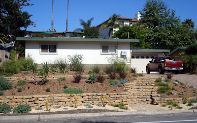 We reused the concrete from the driveway to construct two retaining walls and a stairway.New drought tolerant plantings will anchor the house to the landscape and provide year round low maintenance interest. (two months after installation)