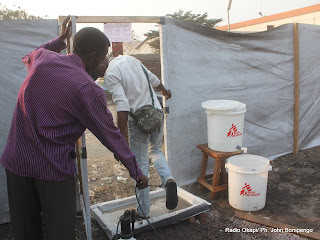 De gauche à droite, un préposé de MSF désinfecte, un homme sortant du centre de prise en charge des victimes de l’épidémie du choléra à Kinshasa. Radio Okapi/ Ph. John Bompengo