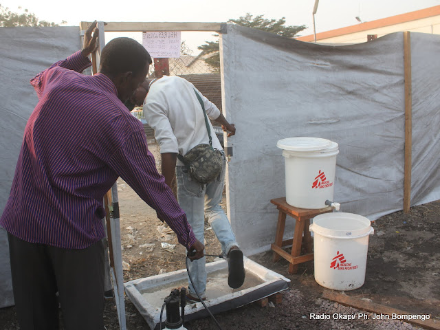De gauche à droite, un préposé de MSF désinfecte, un homme sortant du centre de prise en charge des victimes de l’épidémie du choléra à Kinshasa. Radio Okapi/ Ph. John Bompengo
