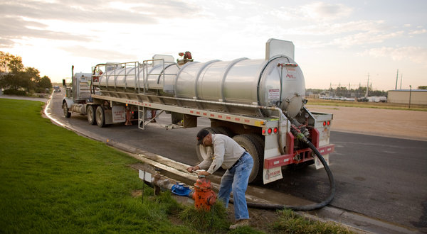 Bob Bellis filled his tanker at a hydrant in Greeley, Colorado, in August 2012 to supply a drilling site. Lease deals with oil companies are important revenue sources for cities. Matthew Staver for The New York Times