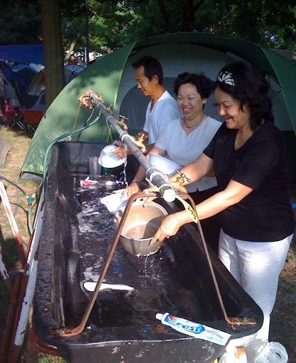 Many visitors to Marian Days set up tents and camp out during the celebration.  Here, campers wash dishes after breakfast.