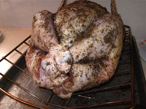 Inside, we place the turkey on the cooking rack, then cover it with the salt-and-pepper rub and stuff the cavity. A sheet pan beneath it keeps the counter clean. Inside, we place the turkey on the cooking rack, then cover it with the salt-and-pepper rub and stuff the cavity. A sheet pan beneath it keeps the counter clean.