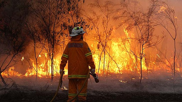 An Australian firefighter faces a bushfire. Jonathan Carroll