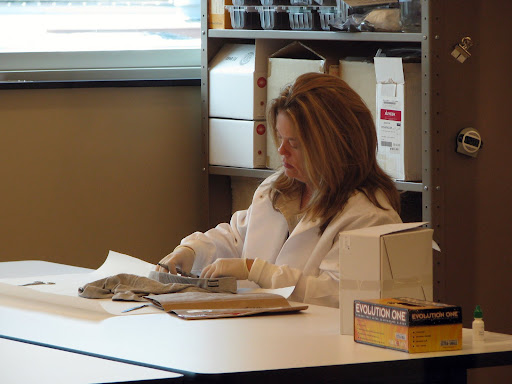 A DNA lab technician processing evidence from an item of clothing. (Photo credit: Jeremy Shreckhise)