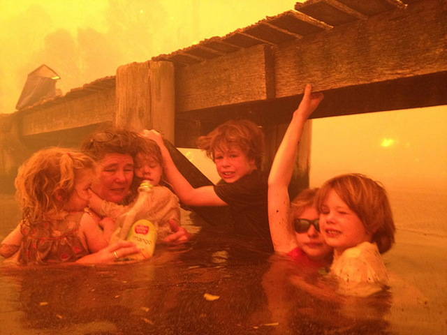 A Tasmanian family takes refuge from record wildfires in the seawater under a jetty, 8 January 2013. Tammy Holmes (second from left) and her grandchildren, (from left) Charlotte, Esther, Liam, Matilda, and Caleb, survived the bushfires that raged for three hours. Photo: Tim Holmes / AP