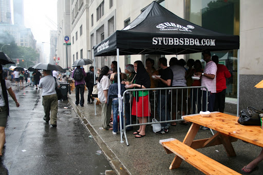 An afternoon rainshower wasn't enough to keep thousands of New Yorkers from chowing down at the BBQ Party, but it did inspire some huddled masses to form under every available tent.