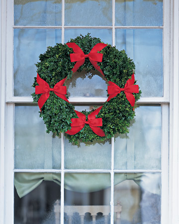 This wreath made with boxwood and embellished with a quartet of slim satin bows captures the classic Christmas pairing of red and green. This wreath made with boxwood and embellished with a quartet of slim satin bows captures the classic Christmas pairing of red and green.