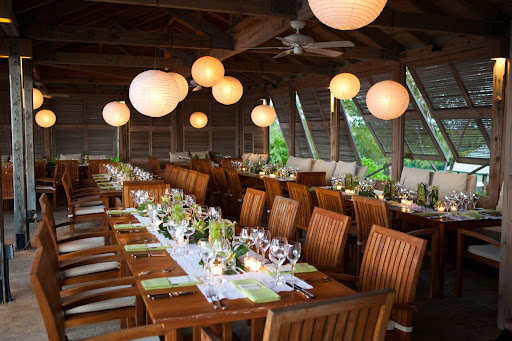 The indoor-outdoor restaurant has teak furniture and beamed ceilings. The green centerpieces stand out on the white table runners. The indoor-outdoor restaurant has teak furniture and beamed ceilings. The green centerpieces stand out on the white table runners.