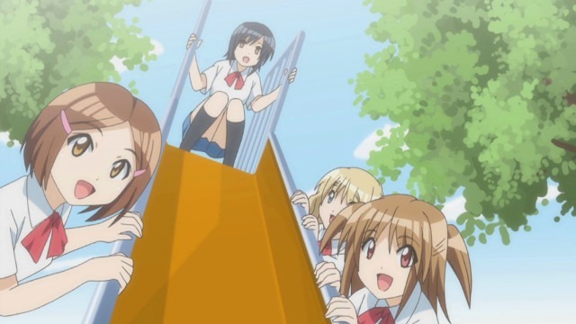 The main four girls pose for the camera around a playground slide