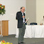 Foto tirada no dia 26 de novembro de 2007, na qual Bassalo está prestando uma homenagem ao seu amigo Carlos Alberto Dias, por ocasião do Seminário: 70 Anos de Carlos A. Dias, ocorrido no Auditório do LENEP, em Macaé, Rio de Janeiro. Sentado, quem preside a sessão é o Professor Fernando Moraes. (A foto foi tirada pelo Professor Amin Bassrei.).