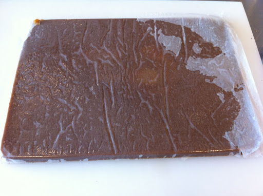 Peeling back the parchment after inverting the caramels onto a greased cutting board.