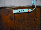 The surge bar is mounted to the wall using Velcro strips and plugged into a three prong, heavy duty extension cord.