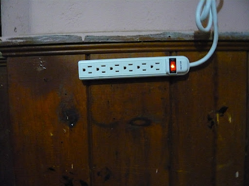 The surge bar is mounted to the wall using Velcro strips and plugged into a three prong, heavy duty extension cord.