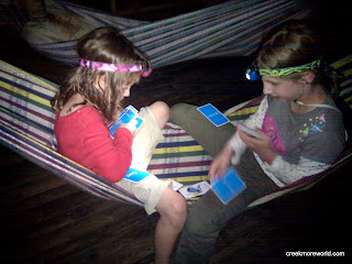 The girls play cards in the hammock at night. The girls play cards in the hammock at night.