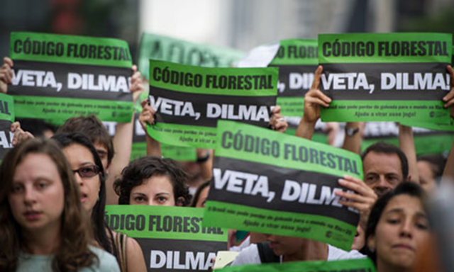 Protesters raise banners demanding that the Brazilian president, Dilma Rousseff, vetoes a forest code approved by the congress in April 2012. Yasuyoshi Chiba / AFP / Getty Images