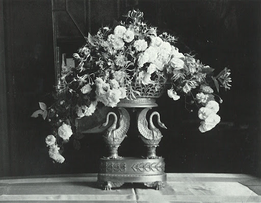 An ormolu vase overflows with Félicité et Perpétue roses and honeysuckle blossoms. An ormolu vase overflows with Félicité et Perpétue roses and honeysuckle blossoms.
