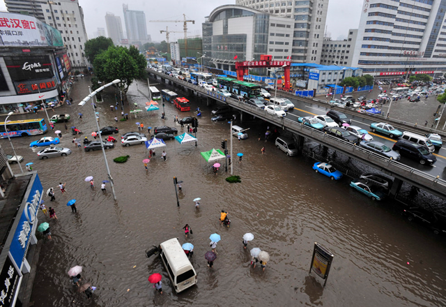 Motorists and people wade through floodwaters in Wuhan in central China's Hubei province on Saturday, 18 June 2011. AP / CHINATOPIX / blogs.sacbee.com