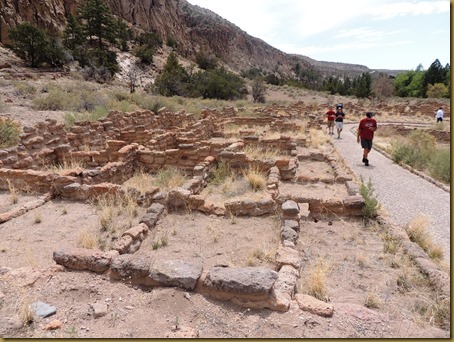 Stone remnants of canyon floor dwellings with Vic walking on the path