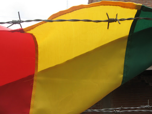 Foto de s&iacute;mbolo patrio boliviano, su bandera tras los alambres de p&uacute;as