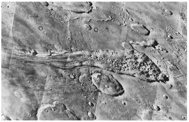 The sinous rille (a relatively long, narrow, trench- or cracklike valley) at the top of this mosaic of 8 photos is believed by some scientists as indicative of flooding of the high plateau in the vicinity of an alternative landing site (known as Capri) for Viking Lander 2. In the foreground is a valley that may have been caused by downfaulting of the martian crust. The hummocks (rounded or conical knolls or mounds of comparatively small elevation) on the valley floor look like chaotic terrain. Some scientists have suggested that the subsidence may be partially caused by melting of the subsurface ice. The large areas of the collapsed terrain show the regional extent of this phenomenon. These views were taken by Viking 1 on July 3, 1976 from a range of 2300 kilometers (1400 miles) and cover an area of about 300 x 300 kilometers (180 x 180 miles). South is toward the top as seen from the spacecraft. 