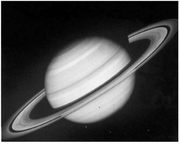 Image of Saturn and its rings floating mysteriously in space taken by the Voyager 2 spacecraft. The sun comes from below so that the ball of Saturn casts a shadow on the rings, and the inner Crepe Ring in turn forms a shadow on Saturn. Also visible are three icy satellites Tethys, Dione and Rhea in the foreground. The shadow of the leftmost satellite Tethys is projected onto the atmospheric cloud deck of Saturn (NASA picture). This figure is available in full color at http://www.mrw.interscience.wiley.com/esst.