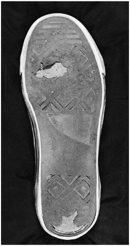  Outsole of a running shoe, showing wear areas on the ball of the foot and the heel.