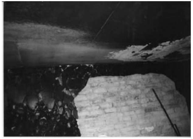 Plaster spalled from a wall as a result of cooling by fire fighting jets. The direction of the spray can be seen from displaced soot on the ceiling.