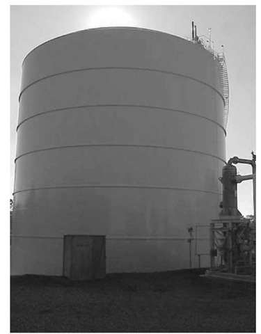  Liquefied natural gas (LNG) storage tank with remote heat vaporizer in right foreground. Note relief valve stacks on tank top. 
