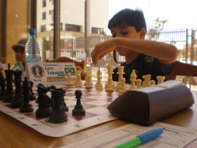 um homem reorganiza uma peça em um tabuleiro de xadrez, um jogo de