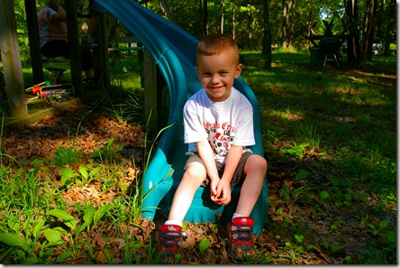 Austin sitting at the bottom of slide with shoes on wrong feet