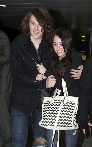 12-15-09 London, UK Teen sensation Miley Cyrus feels the winter chill as she wraps up with a friend to battle the cold weather at Heathrow Airport. EXCLUSIVE PIX by Flynet ©2009 818-307-4813 Nicolas