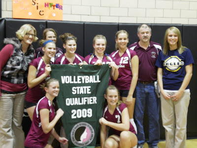 Pella Christian Seniors and Coaching Staff pose with the State Volleyball Qualifier Banner after defeating #8 Mediapolis 3-0