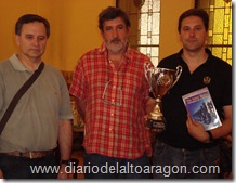 el MF. Javier Fontana con su trofeo de vencedor y material de ajedrez posando con Juan Carlos González (centro) y Roberto Cifuentes (izquierda). 