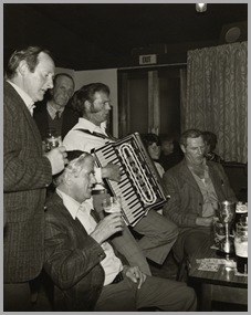 The Danby and District League Open Quoits Championship.Winner John White (right) celebrating, accompanied by Ed White on the piano accordion.The League championship was held during '79 at the Rifle Club Ground, Whitby.  Whitby Rifle Club, on the west side of Whitby, has a splendid rifle range as well as 3 outdoor quoit grounds and 2 indoor grounds.The indoor grounds allow a winter quoit league of nine five-a-side teams to thrive.