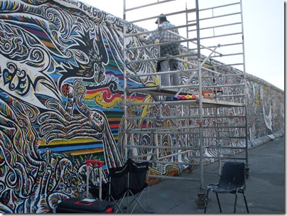 Un artista dipinge sulla east side gallery