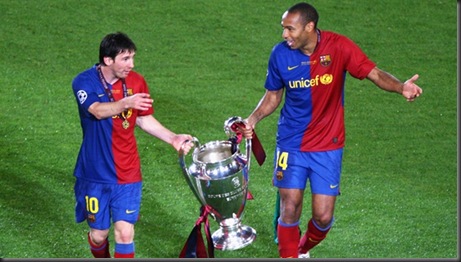 Lionel Messi and Thierry Henry holding Barcelona's Champions League Trophy