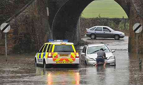 A motorist is helped by military after removing stranded on a flooded highway in Essex