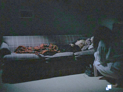 Ann kneels beside Graham as he sleeps