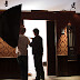 Director, Lindsay Mann watches as Set Decorator, Savio Pham works on the door
