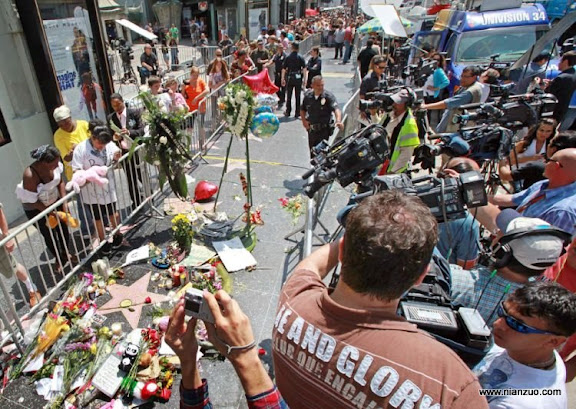 关于杰克逊 Visitors pay their respects as news crews record a sidewalk shrine of mementoes, flowers, candles and notes adorning the star of Michael Jackson on the Hollywood Walk of Fame in Los Angeles Friday, June 26, 2009.&nbsp;&nbsp;Jackson died Thursday of an apparent heart attack.&nbsp;&nbsp;(AP Photo/ Reed Saxon)
