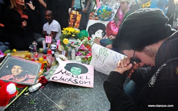关于杰克逊 Jesse Buckingham, 24, of Los Angeles, sits at a sidewalk shrine of flowers, candles and notes adorning the star of Michael Jackson on the Hollywood Walk of Fame in Los Angeles Friday, June 26, 2009.&nbsp;&nbsp;Jackson died Thursday of an apparent heart attack.&nbsp;&nbsp;(AP Photo/ Reed Saxon)