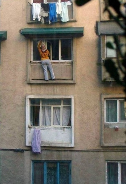 Mujer limpiando las ventana con mucho riesgo