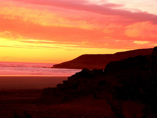 coucher de soleil rivage falaise et plage mer rosée ciel nuageux blanc jaune et orange côte atlantique Maroc