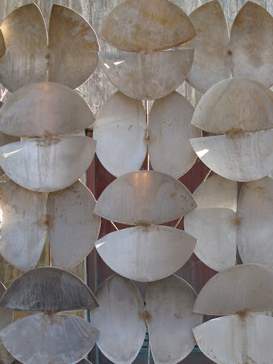 Sculpture by Harry Bertoia lines a garden wall.