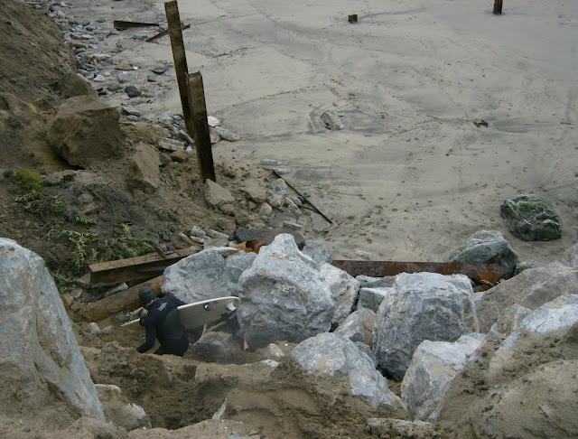 Surfer climbing down eroded bluff to Ocean Beach